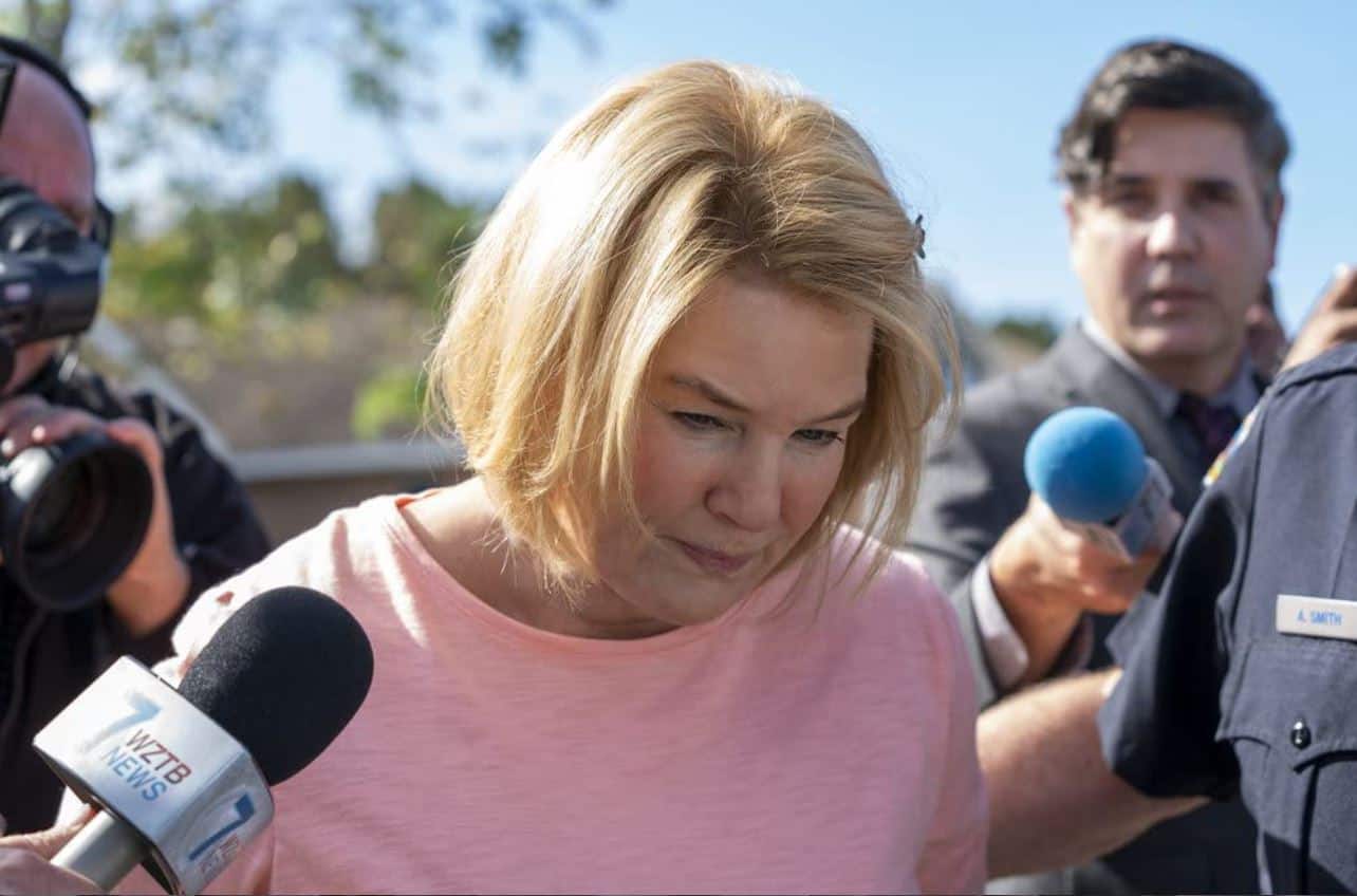 Pam Hupp in a pink shirt escorted by police in the show The Thing About Pam