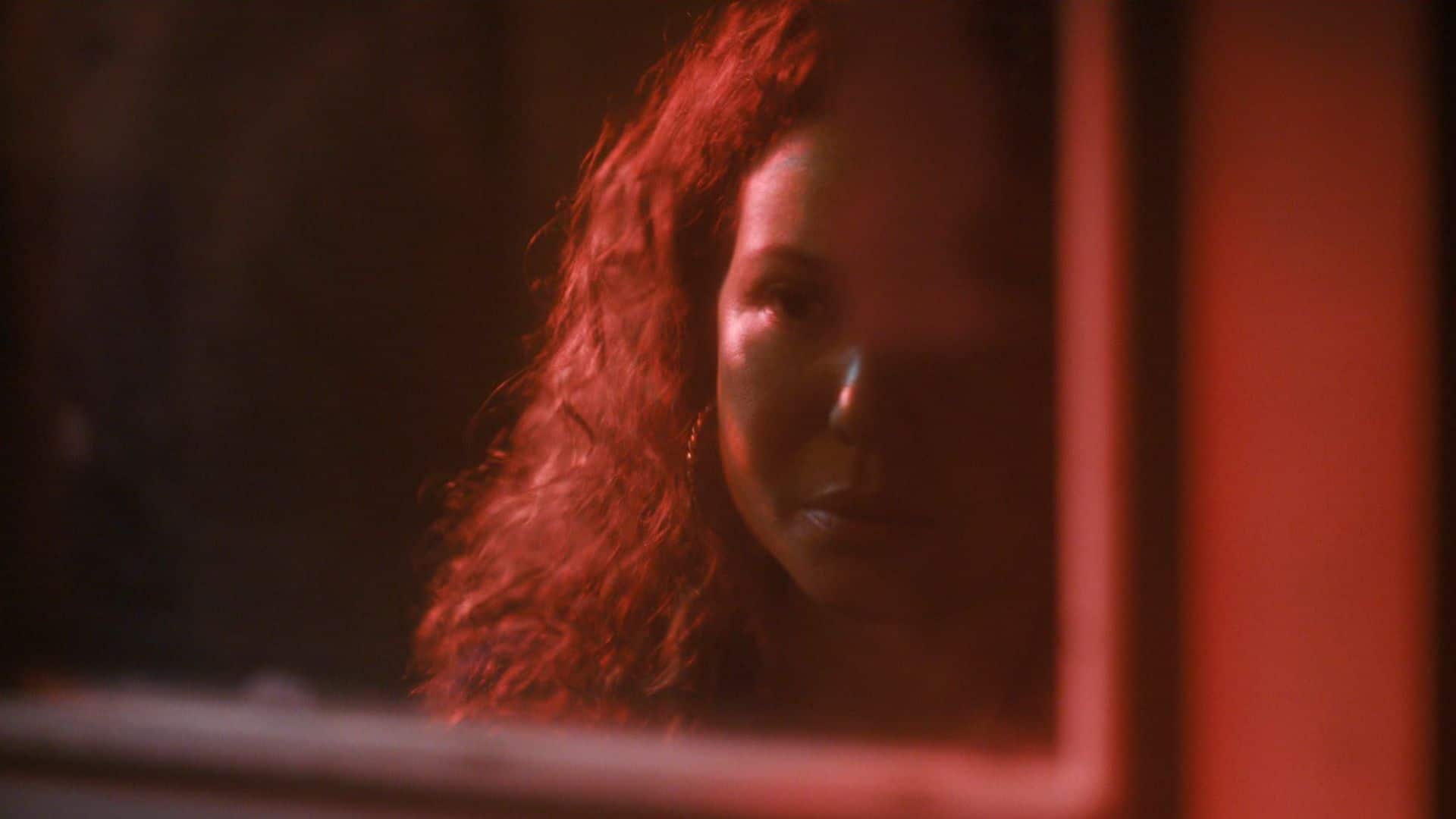 Justina Machado bathed in red light in this image from Amazon Studios