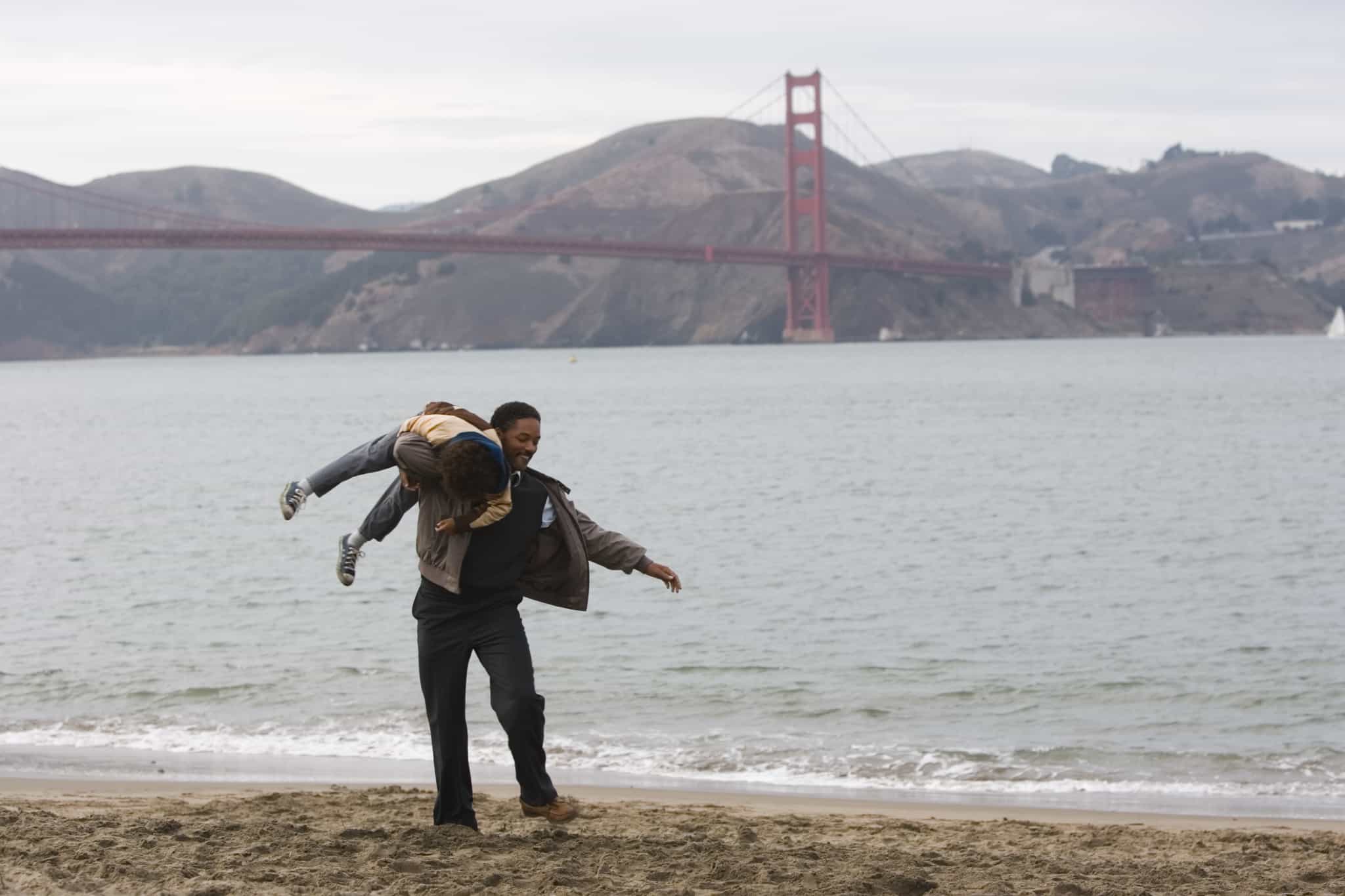 Chris playfully throws his son over his shoulder in front of the Golden Gate Bridge