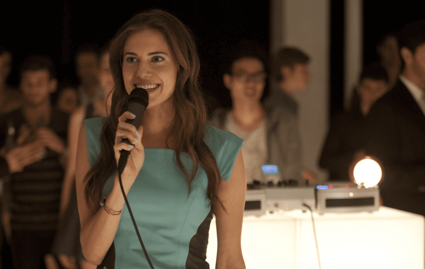 Marnie standing in the middle of a dance floor and holding a microphone in this image from Apatow Productions