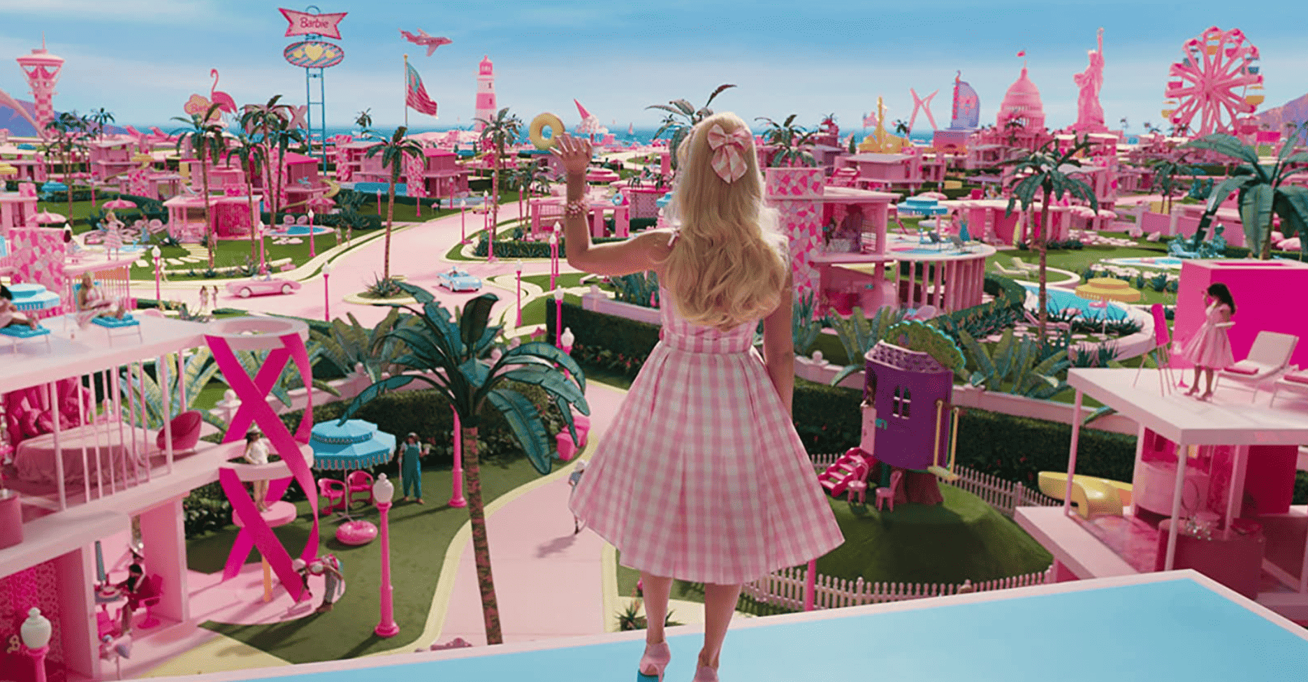 Barbie waves from the rooftop of her dollhouse and presides over the rest of Barbieland in this image from Warner Bros