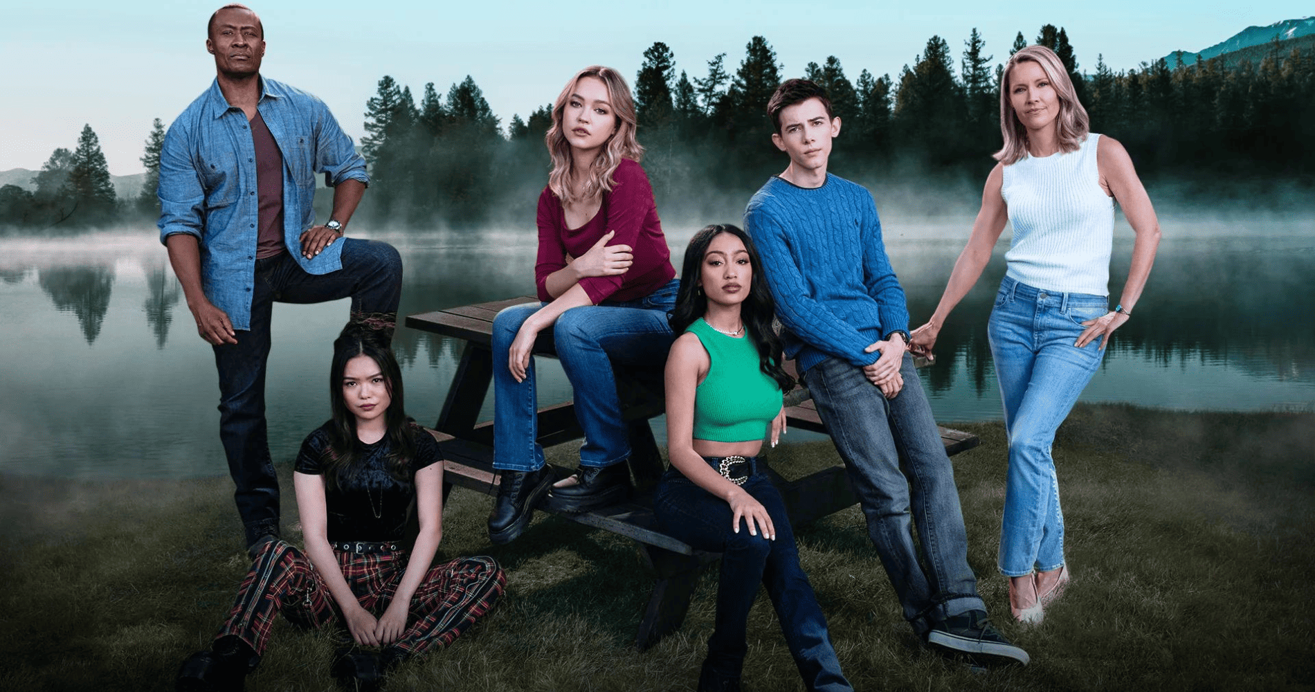 A group of people sits outdoors with a lake in the background in this photo by Entertainment One