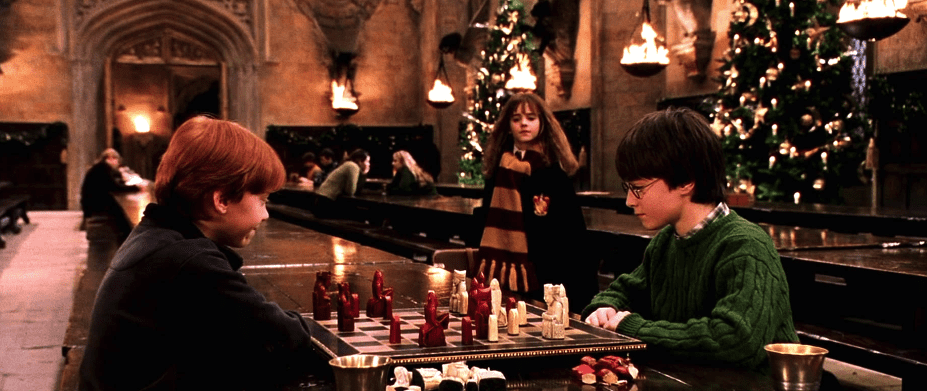 Ron and Harry play wizards’ chess in the Great Hall as Hermione watches