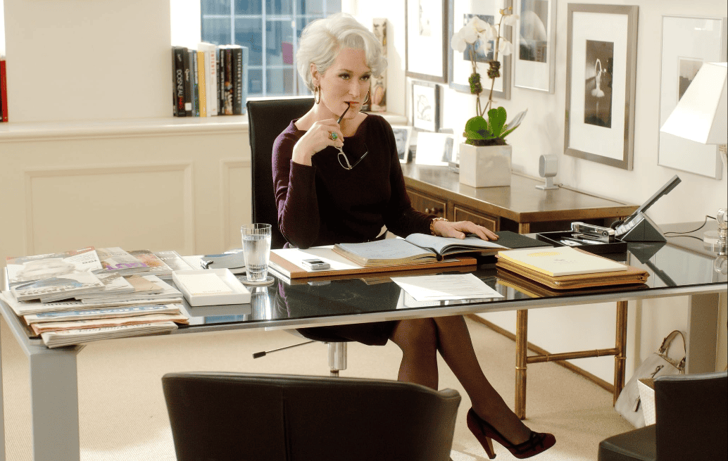 A woman sits at her desk while biting on her glasses in this image from Fox 2000 Pictures.