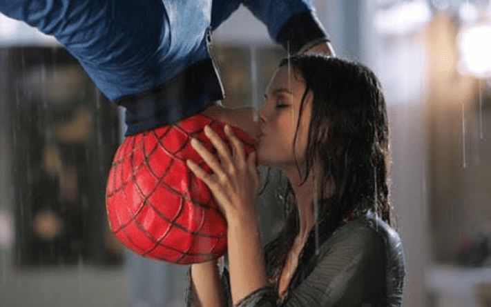 Spider-man hangs upside down and kisses a woman in the rain in this image from Warner Bros. Studios
