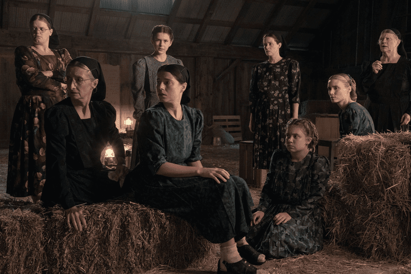 The women sitting on straw bales in a barn